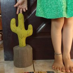 a person standing next to a cactus plant on top of a wooden stand with their feet up