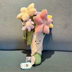 a stuffed animal holding a bouquet of flowers with a tag on it's side