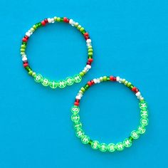 two green and red bracelets sitting on top of a blue surface