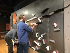 two men are looking at the wall with different types of objects on it