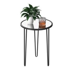 a small table with a plant on top and two glasses sitting on the table next to it