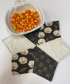 a bowl of candy corn sitting on top of two placemats next to each other