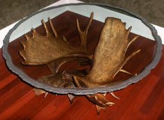 a wooden table topped with a metal bowl filled with antlers