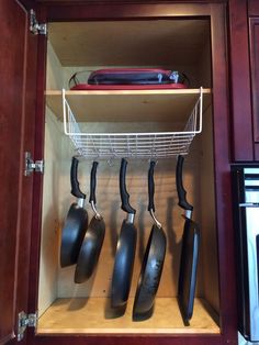 pots and pans are hanging in the cabinet