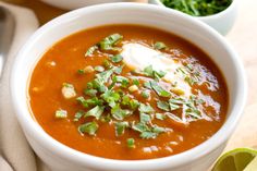 two white bowls filled with soup and garnished with sour cream