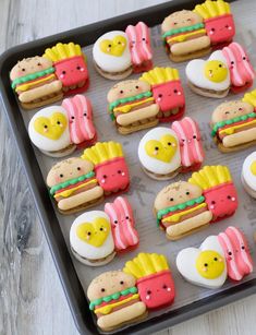 decorated cookies in the shape of hamburgers and hotdogs on a baking sheet