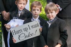 three young boys in suits holding a sign that says hurry up i want cake