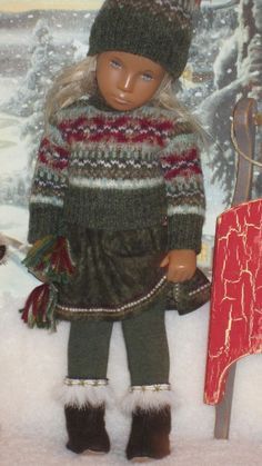 a doll is standing in the snow next to a sled