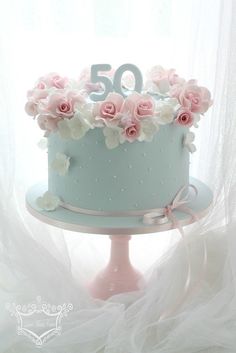 a blue cake with pink flowers on top and the number 50 on it's side