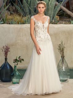 a woman in a wedding dress standing next to some vases