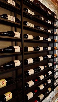 a wine rack filled with lots of bottles next to a brick wall in a room