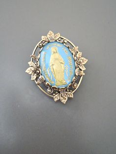 "Vintage Jewelry - Vintage Brass - Blue Brooch - Mother Mary Jewelry - Catholic Brooch - Religious Jewelry - handmade jewelry This is such a pretty brooch! Vintage brass setting embellished with a vintage light blue and gold vintage cameo of the Mother Mary. Exquisite detail with a rich patina on the brass. This is a real special piece. Chloe says, \"Wear it and feel fabulous!\" The pendant is 1 1/4\" long Thanks for visiting Chloe's" Blue Brooch Lapel Pin As Gift, Antique Blue Collectible Brooches, Antique Handmade Blue Brooches, Blue Brooch Pin For Gift, Blue Brooch Pins As A Gift, Blue Brooch Pin As Gift, Blue Brooch Pins For Gift, Vintage Blue Jewelry For Memorial, Blue Vintage Jewelry For Memorial