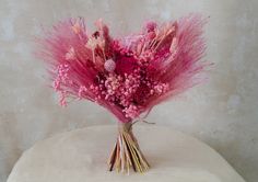 a bouquet of pink flowers sitting on top of a white cushion