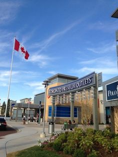 a canadian flag flying in the air over a shopping center