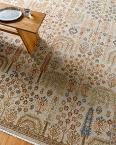 a table with a plate on top of it in front of a large rug that has an ornate design