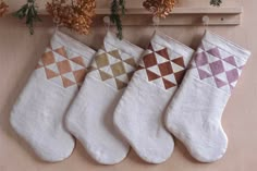 three christmas stockings hanging on a wall with pine cones in the background and text overlay