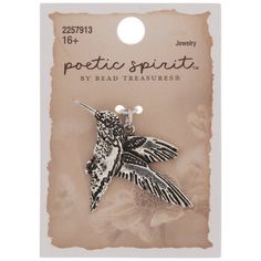 a white and black hummingbird pin with flowers on it's back side, in front of a card