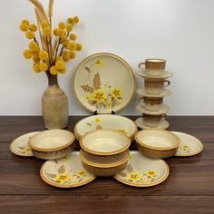 a table topped with lots of plates and vases filled with yellow flowers next to each other