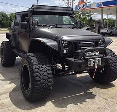 a black jeep parked in front of a gas station