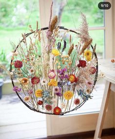 a hanging basket filled with lots of different types of wildflowers in front of a window