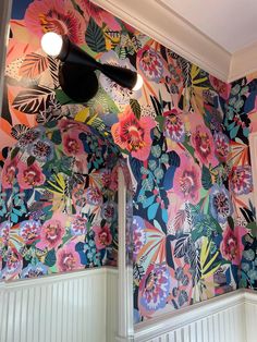 a colorful wallpapered room with flowers on the walls and lights hanging from the ceiling