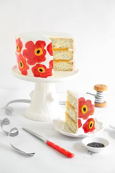 the cake is decorated with red flowers and has two slices cut from it, along with other tools