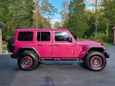 a bright pink jeep parked in a driveway