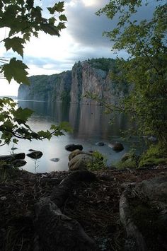 a person sitting on the edge of a cliff looking out over a body of water