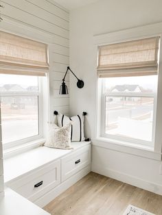 a white room with two windows and some pillows