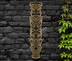 a wooden carving on the side of a brick wall next to a potted plant