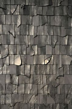 a wall made out of metal tiles with different shapes and sizes on the sides, including one