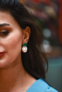 a close up of a person wearing some kind of earring with pearls on it