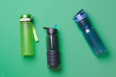 three different types of water bottles are on a green surface, one is blue and the other is black