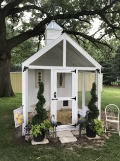 a small white shed with potted plants in it