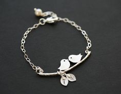 "A great gift for a mother, this kissing bird on branch bracelet consists of: 1. a matte white gold plated \"kissing birds on branch\" charm 2. one or more matte white gold plated leaf (or bird) charms, each stamped with an initial 3. a freshwater pearl 4. a sterling silver chain closed with a lobster clasp All findings are sterling silver Packaged my shop's premium quality gift box (pictured) Please use the dropdown menu to select the number/type of charms and leave initial(s) in your note to s Branch Bracelet, Monogram Bracelet, Bracelet Initial, Leaf Bracelet, Bird On Branch, Initial Bracelet, Leaf Charms, Cute Bracelets, Charm Bracelets