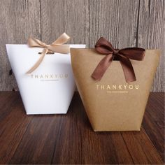 two brown and white bags with bows on them sitting next to each other in front of a wooden wall