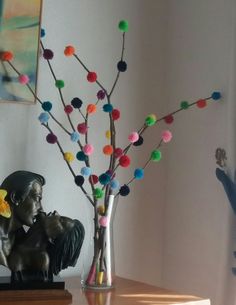 a vase filled with colorful pom - poms next to a statue