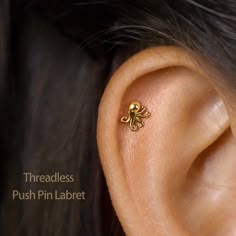 a close up of a person's ear with a small gold flower on it