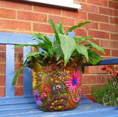 a potted plant sitting on top of a blue bench next to a brick wall