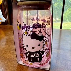 a hello kitty glass cup sitting on top of a wooden table