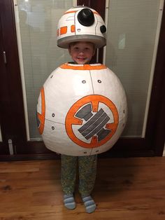 a young boy wearing a star wars bbg helmet and green leggings, standing in front of a door