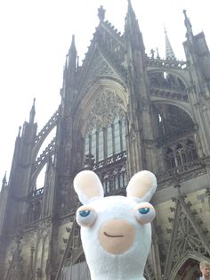 a stuffed animal in front of a large building with people standing around and looking at it