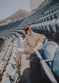 a woman is sitting on the bleachers talking on her cell phone