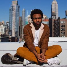 a man sitting on the ground in front of a city skyline