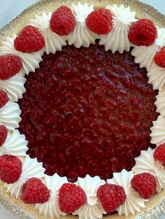 a pie with white frosting and raspberries on top