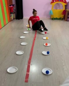 a woman sitting on the floor surrounded by white plates with red tape in front of her