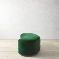 a green foot stool sitting on top of a wooden floor next to a white wall