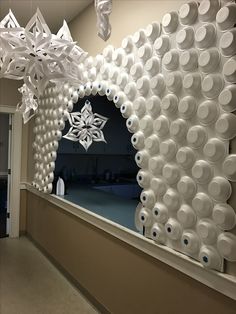 a room filled with lots of white cups and paper snowflakes