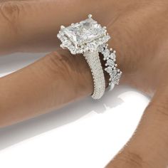 a woman's hand with a diamond ring on top of her finger and an engagement band