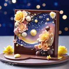 a cake decorated with flowers and chocolates on a plate in front of blurry lights